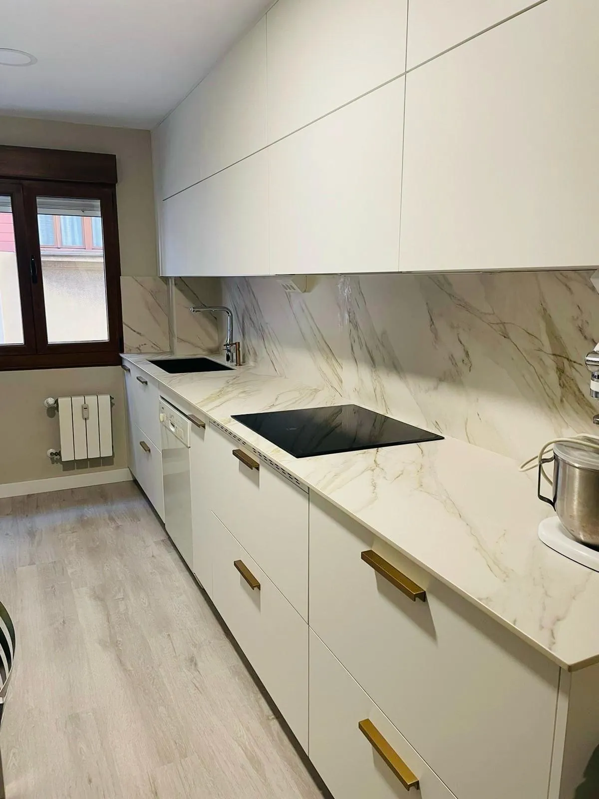Cocina blanca con frente de piedra clara y encimera