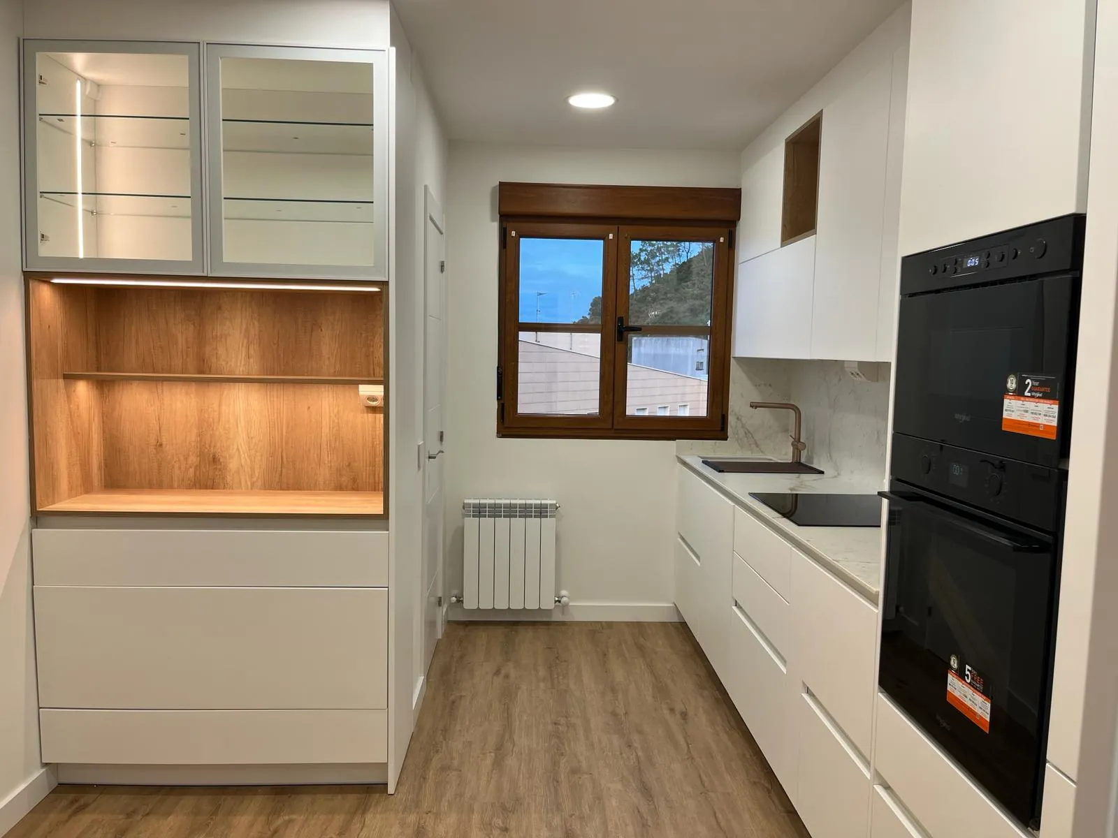 Cocina blanca con veta de madera natural y horno integrado