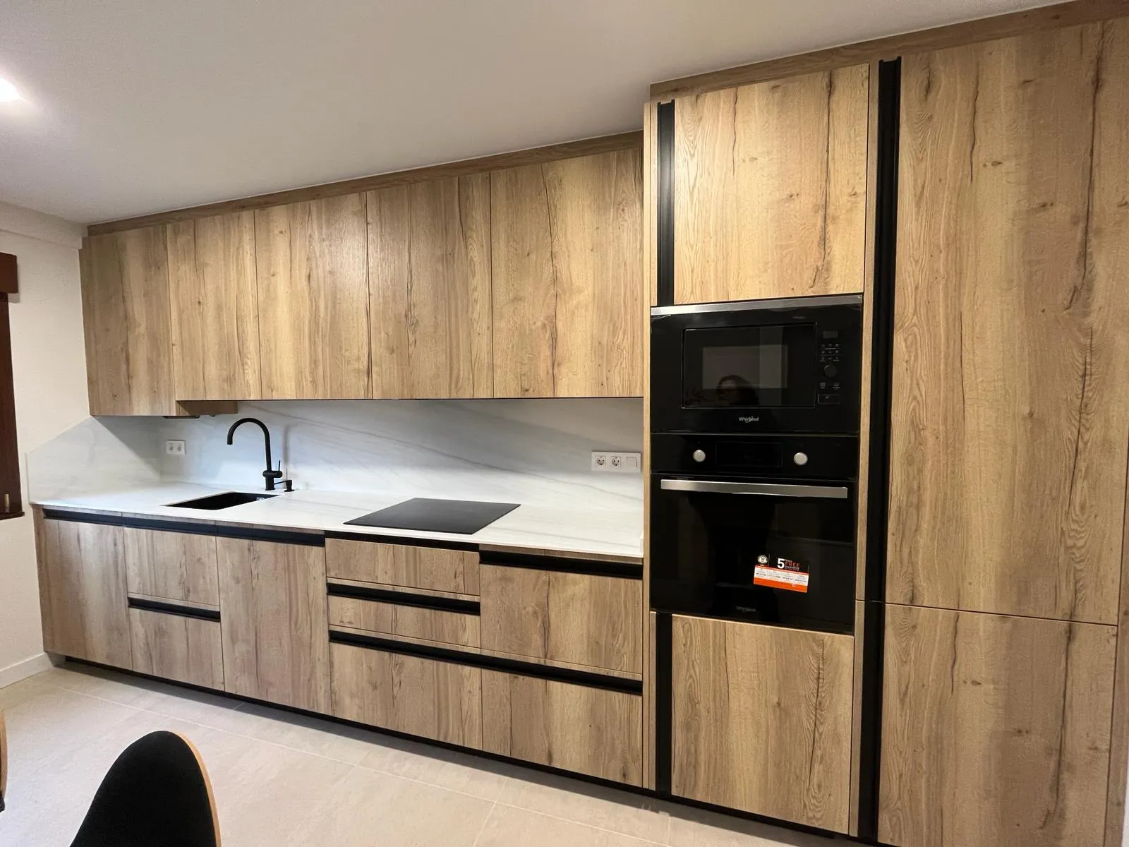 Cocina lineal en roble con encimera blanca y office