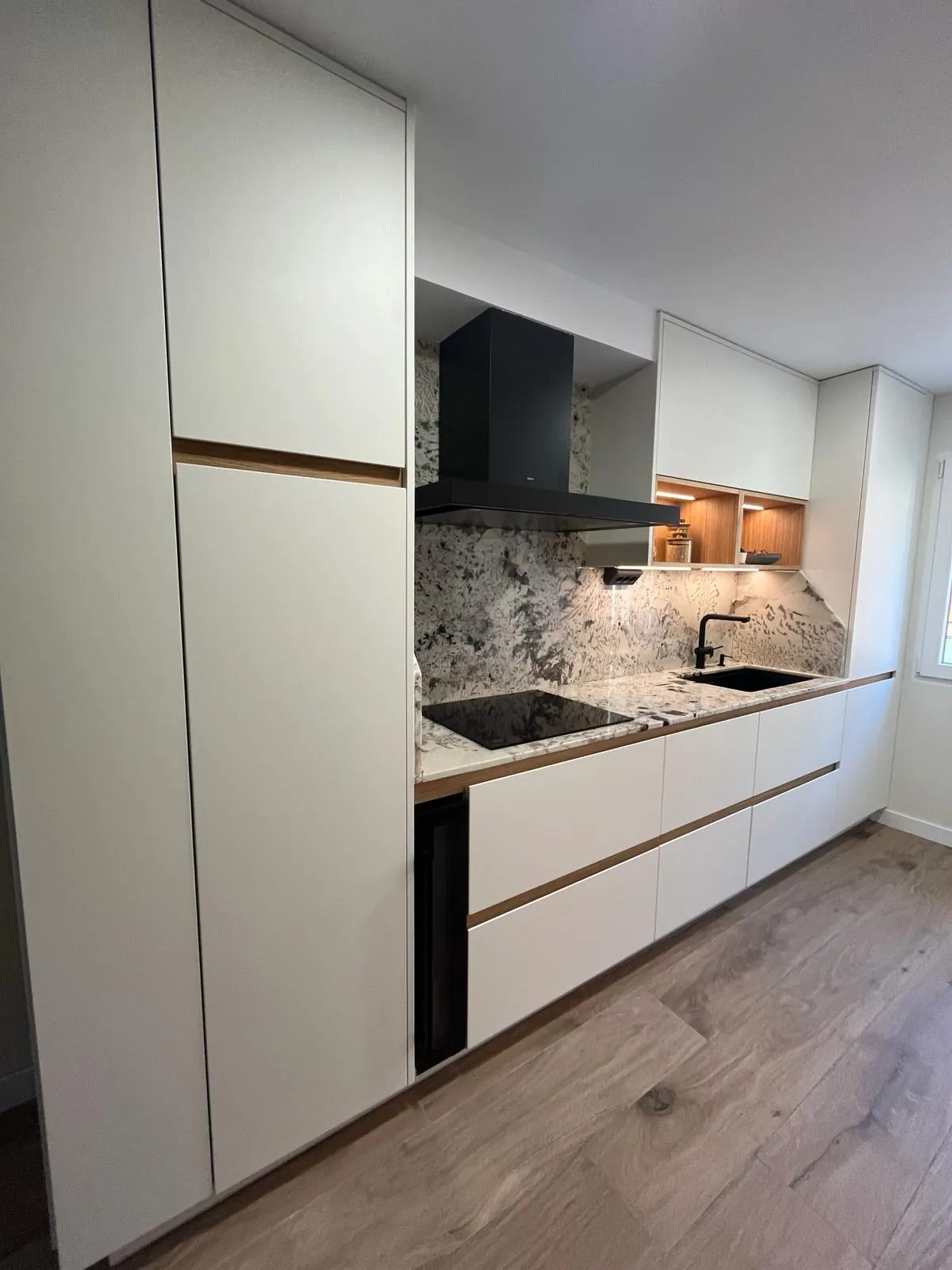 Cocina blanca con frente de piedra y placa integrada