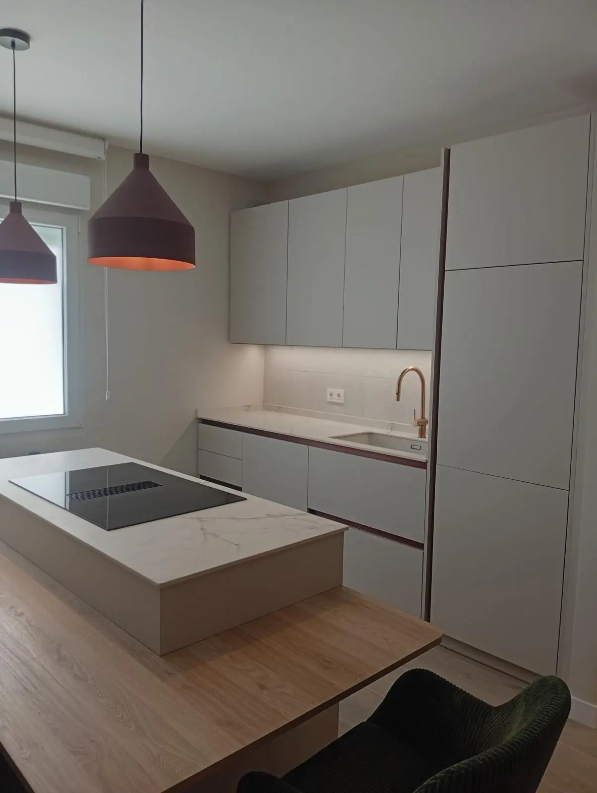 Cocina blanca con isla, grifería dorada y columnas de horno integradas